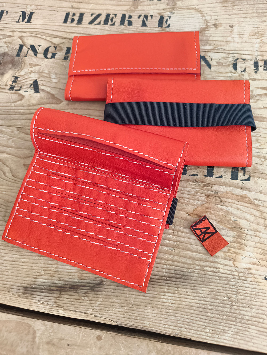 blagues à tabac en agneau plongé rouge vermillon dont le moyen de fermeture est un élastique noir large de 2,5 cm